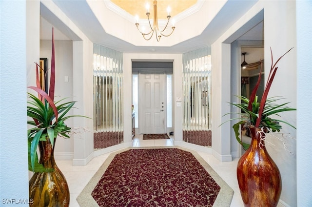 interior space featuring a notable chandelier, a raised ceiling, ornamental molding, tile patterned flooring, and baseboards