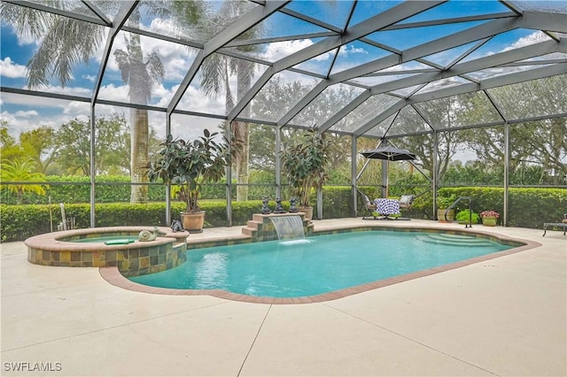 view of pool with an in ground hot tub, pool water feature, glass enclosure, and a patio area