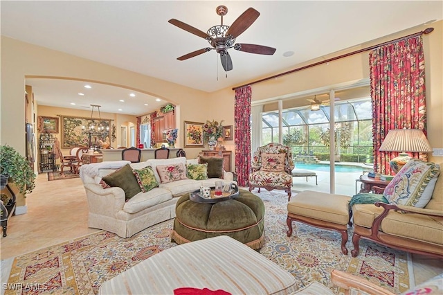 tiled living room with ceiling fan with notable chandelier