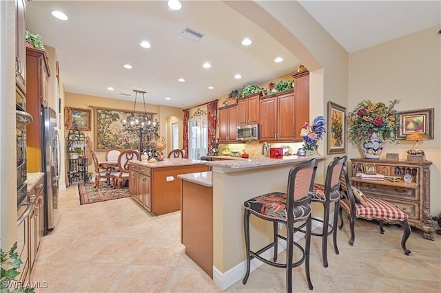 kitchen featuring a breakfast bar, hanging light fixtures, kitchen peninsula, a kitchen island, and stainless steel appliances