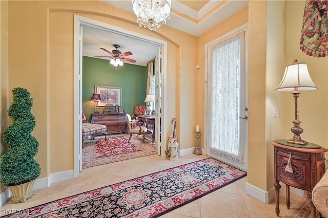 foyer entrance with ceiling fan with notable chandelier, ornamental molding, and light tile patterned flooring