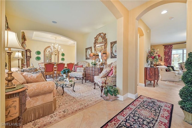 living room featuring an inviting chandelier, light tile patterned floors, and a tray ceiling