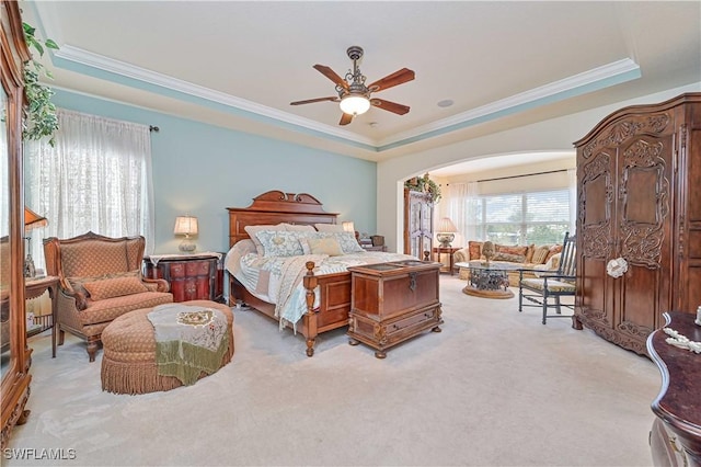 bedroom featuring ceiling fan, ornamental molding, a raised ceiling, and light carpet