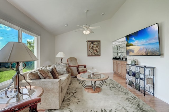 living room with ceiling fan, light hardwood / wood-style flooring, and lofted ceiling