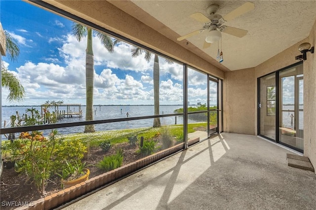 unfurnished sunroom with a water view and ceiling fan