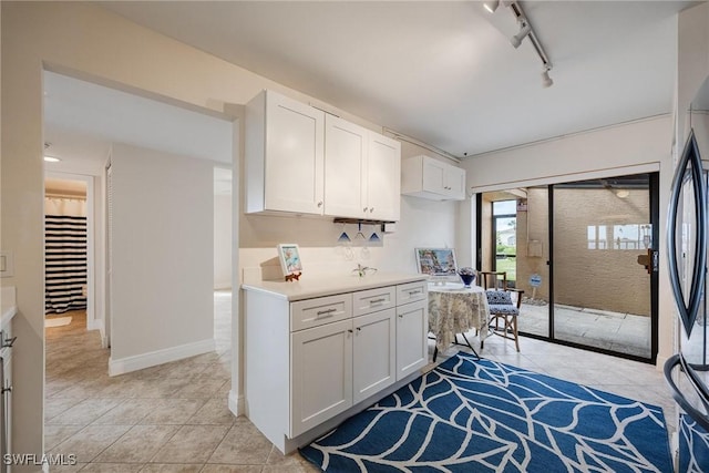 kitchen featuring white cabinetry, light tile patterned flooring, rail lighting, and black fridge