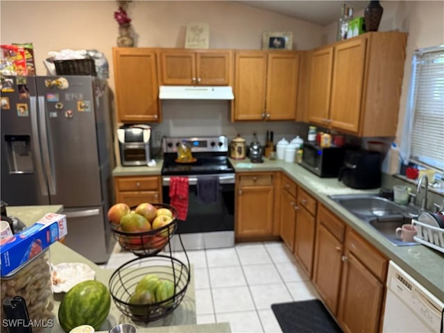 kitchen featuring stainless steel appliances, light tile patterned flooring, vaulted ceiling, and sink