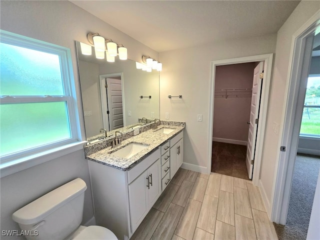 3102 E 2nd St, Lehigh Acres, FL 33936 - full bathroom featuring double vanity, toilet, wood tiled floors, baseboards, and a spacious closet