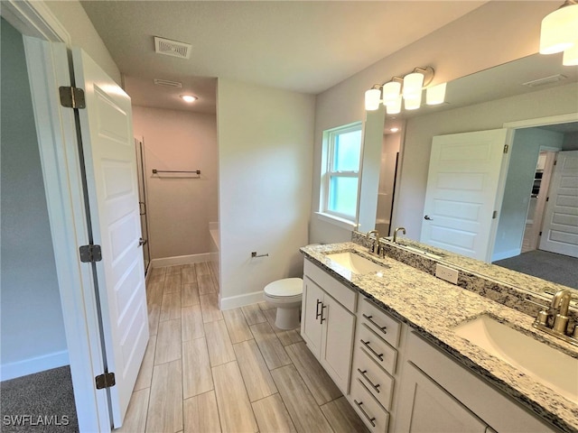 3102 E 2nd St, Lehigh Acres, FL 33936 - bathroom with double vanity, baseboards, toilet, a tub to relax in, and wood finish floors