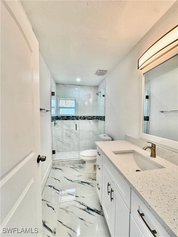 bathroom with vanity, toilet, a textured ceiling, and walk in shower