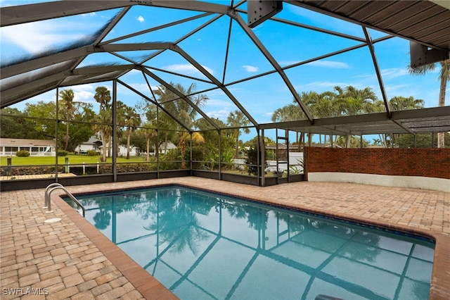 view of pool with glass enclosure and a patio area