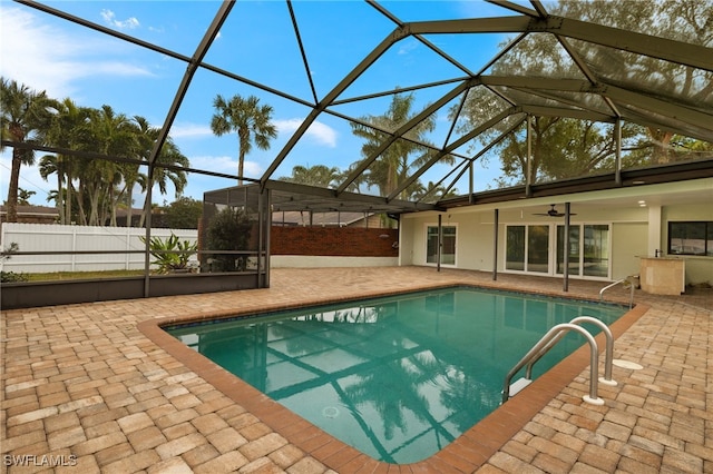 view of pool with glass enclosure, a patio, and ceiling fan