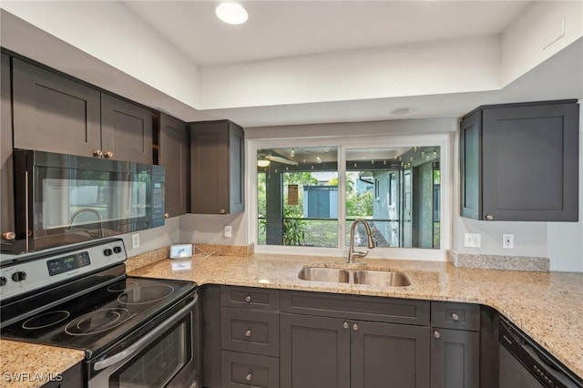 kitchen featuring light stone countertops, sink, and black appliances