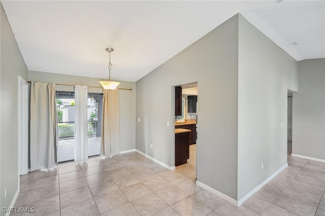 unfurnished dining area with vaulted ceiling and light tile patterned floors