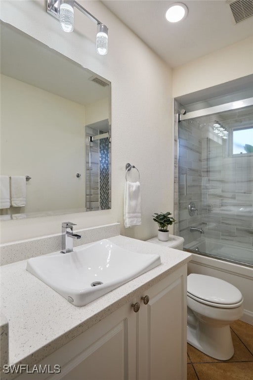 bathroom featuring visible vents, toilet, tile patterned flooring, enclosed tub / shower combo, and vanity