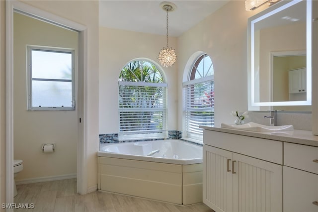 full bathroom featuring a tub with jets, toilet, vanity, and baseboards