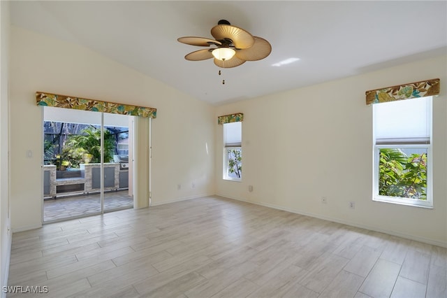 empty room with a wealth of natural light, lofted ceiling, ceiling fan, and light wood finished floors