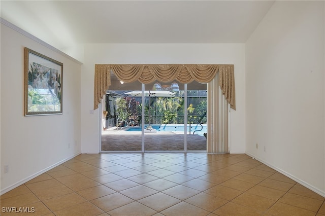 tiled empty room featuring baseboards and a sunroom