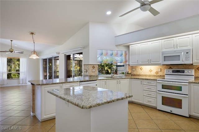 kitchen with white appliances, light tile patterned floors, a peninsula, a sink, and vaulted ceiling