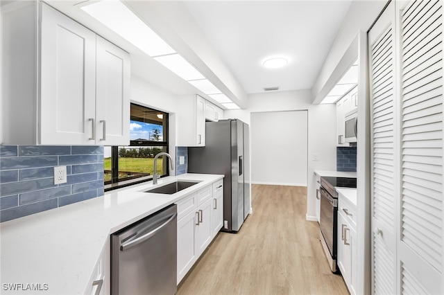 kitchen featuring sink, tasteful backsplash, white cabinetry, light hardwood / wood-style floors, and stainless steel appliances