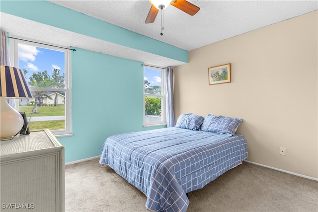 carpeted bedroom featuring a textured ceiling and ceiling fan