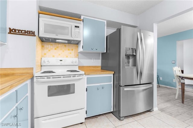 kitchen featuring blue cabinetry, a textured ceiling, light tile patterned floors, white appliances, and decorative backsplash