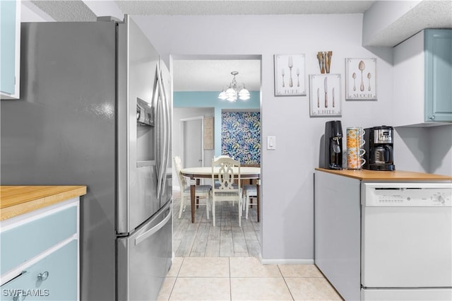 kitchen with stainless steel fridge with ice dispenser, light tile patterned floors, white dishwasher, a notable chandelier, and pendant lighting