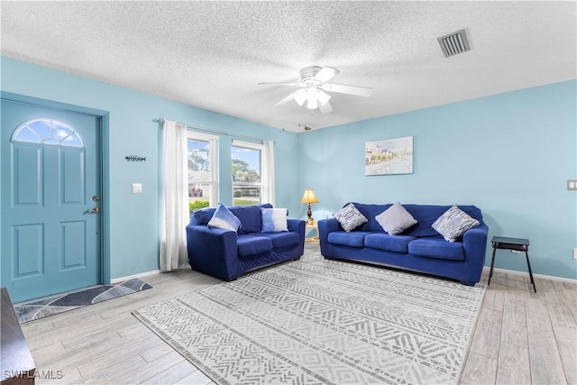 living room with hardwood / wood-style flooring, a textured ceiling, and ceiling fan