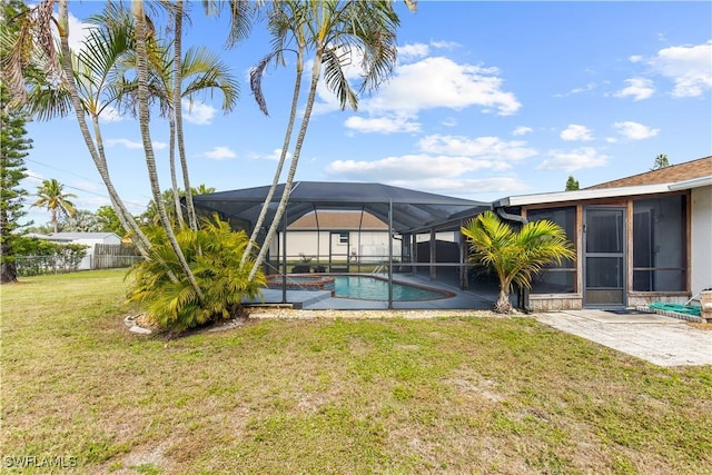 view of pool with a patio area, a lawn, and glass enclosure