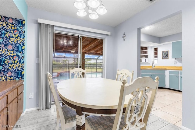 dining area featuring an inviting chandelier, sink, and a textured ceiling