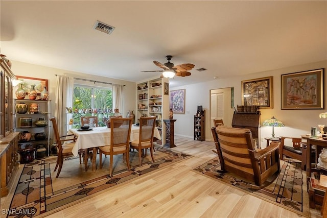 dining room with built in shelves, light hardwood / wood-style flooring, and ceiling fan