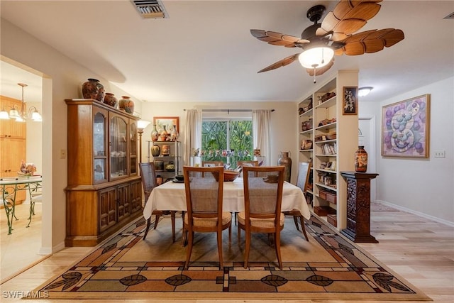 dining area with ceiling fan with notable chandelier, built in features, and light hardwood / wood-style flooring