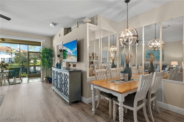 dining space with hardwood / wood-style floors and an inviting chandelier