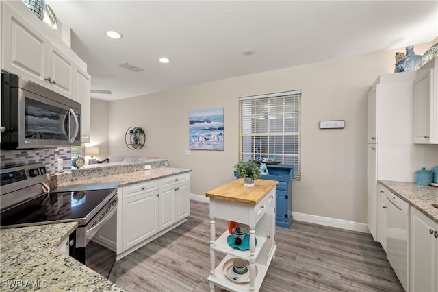 kitchen featuring appliances with stainless steel finishes, wooden counters, white cabinetry, tasteful backsplash, and light hardwood / wood-style flooring