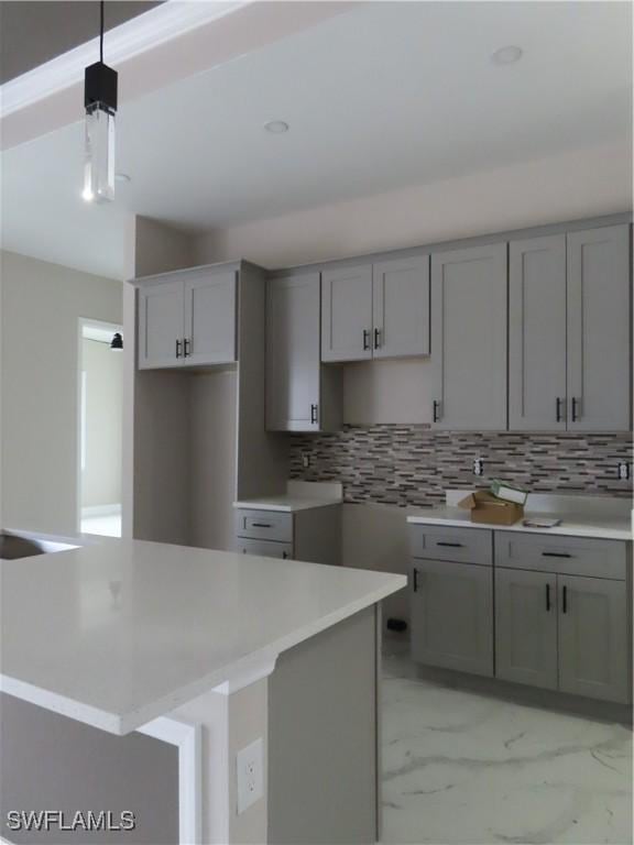 kitchen featuring a kitchen island, backsplash, pendant lighting, and gray cabinetry