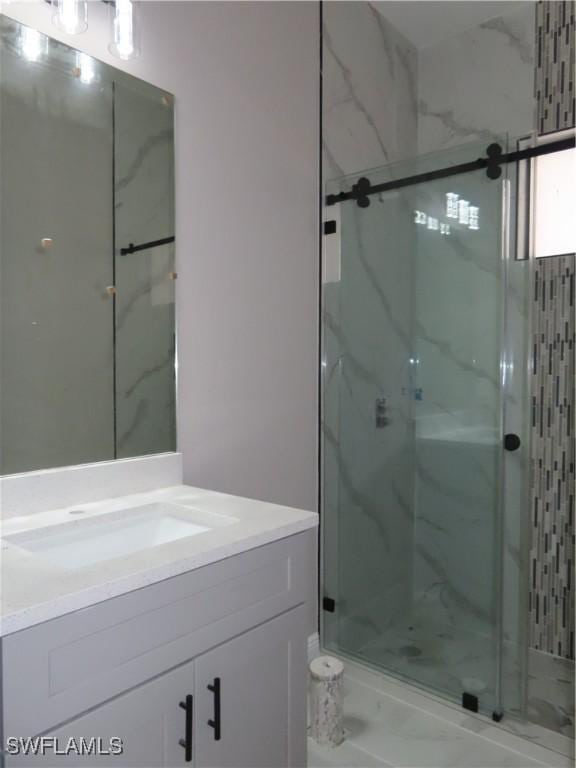 bathroom featuring a shower with door and vanity