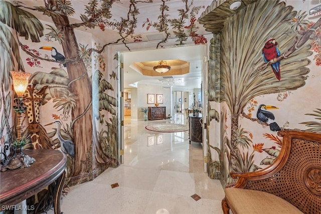 corridor with ornamental molding and a tray ceiling