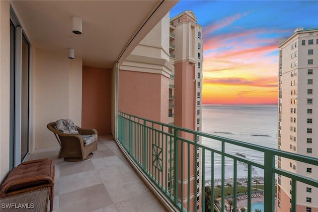 balcony at dusk featuring a water view