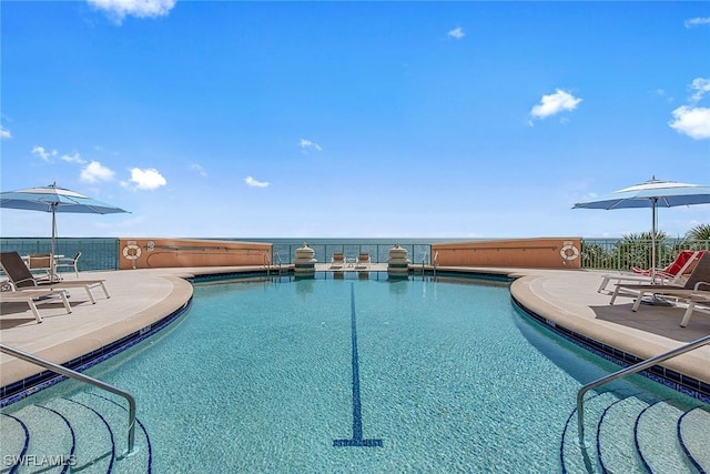 view of swimming pool with a patio and a water view