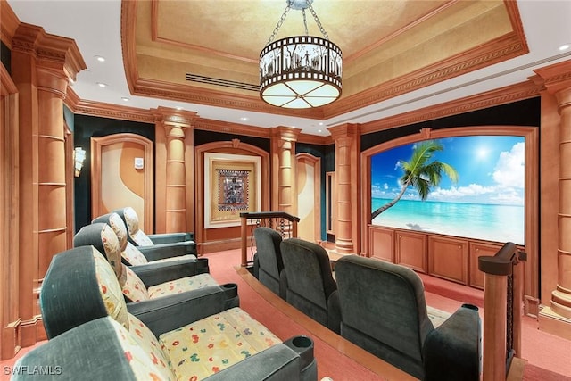 carpeted cinema room with crown molding, a tray ceiling, built in shelves, and ornate columns