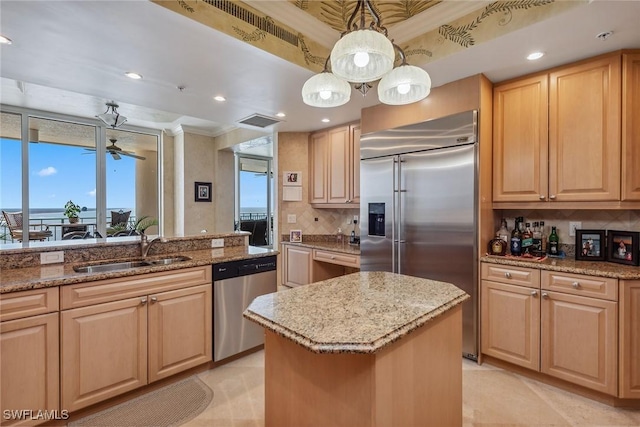 kitchen featuring stainless steel appliances, a kitchen island, light brown cabinets, and decorative light fixtures