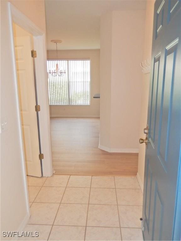 corridor with an inviting chandelier and light tile patterned flooring