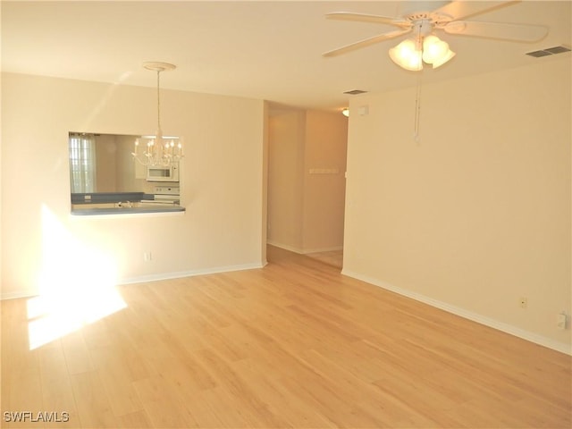 spare room with ceiling fan with notable chandelier and hardwood / wood-style floors