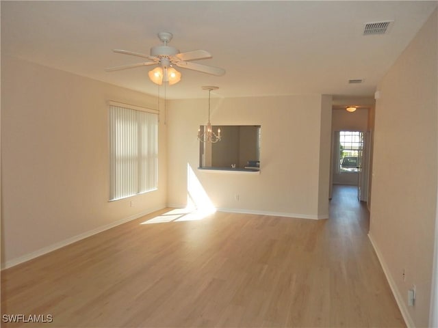 unfurnished living room featuring hardwood / wood-style flooring and ceiling fan with notable chandelier