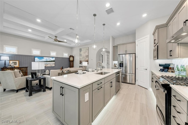 kitchen featuring gray cabinets, appliances with stainless steel finishes, pendant lighting, an island with sink, and sink