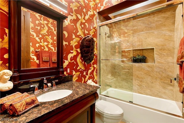 full bathroom featuring toilet, vanity, and bath / shower combo with glass door