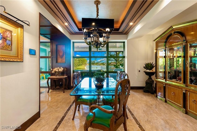 dining space with a chandelier, a tray ceiling, and ornamental molding