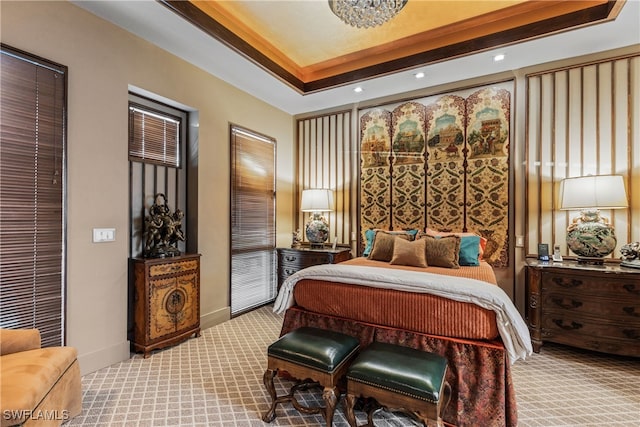 bedroom featuring a tray ceiling and light carpet