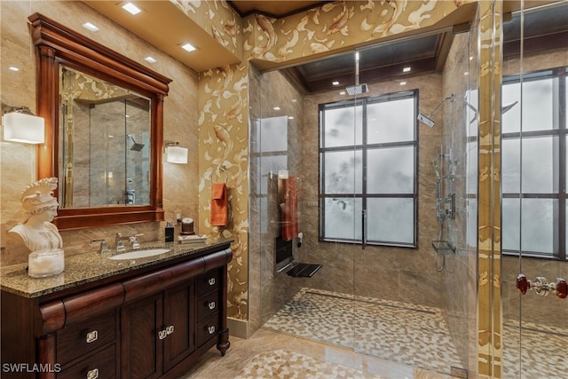 bathroom featuring vanity, a tile shower, and a wealth of natural light