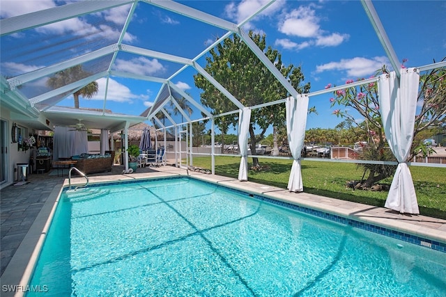 view of swimming pool with a lanai, a lawn, ceiling fan, and a patio area